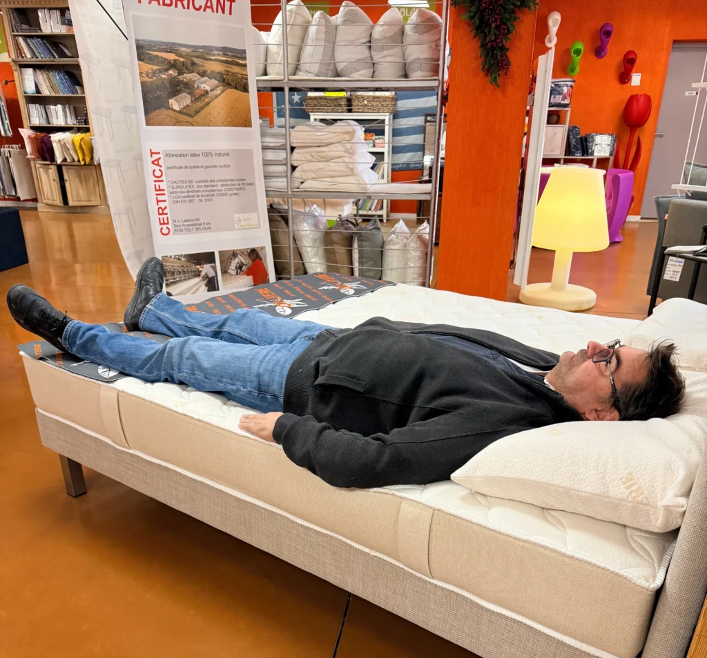 Client allongé sur le dos testant un matelas en magasin OX LITERIE
