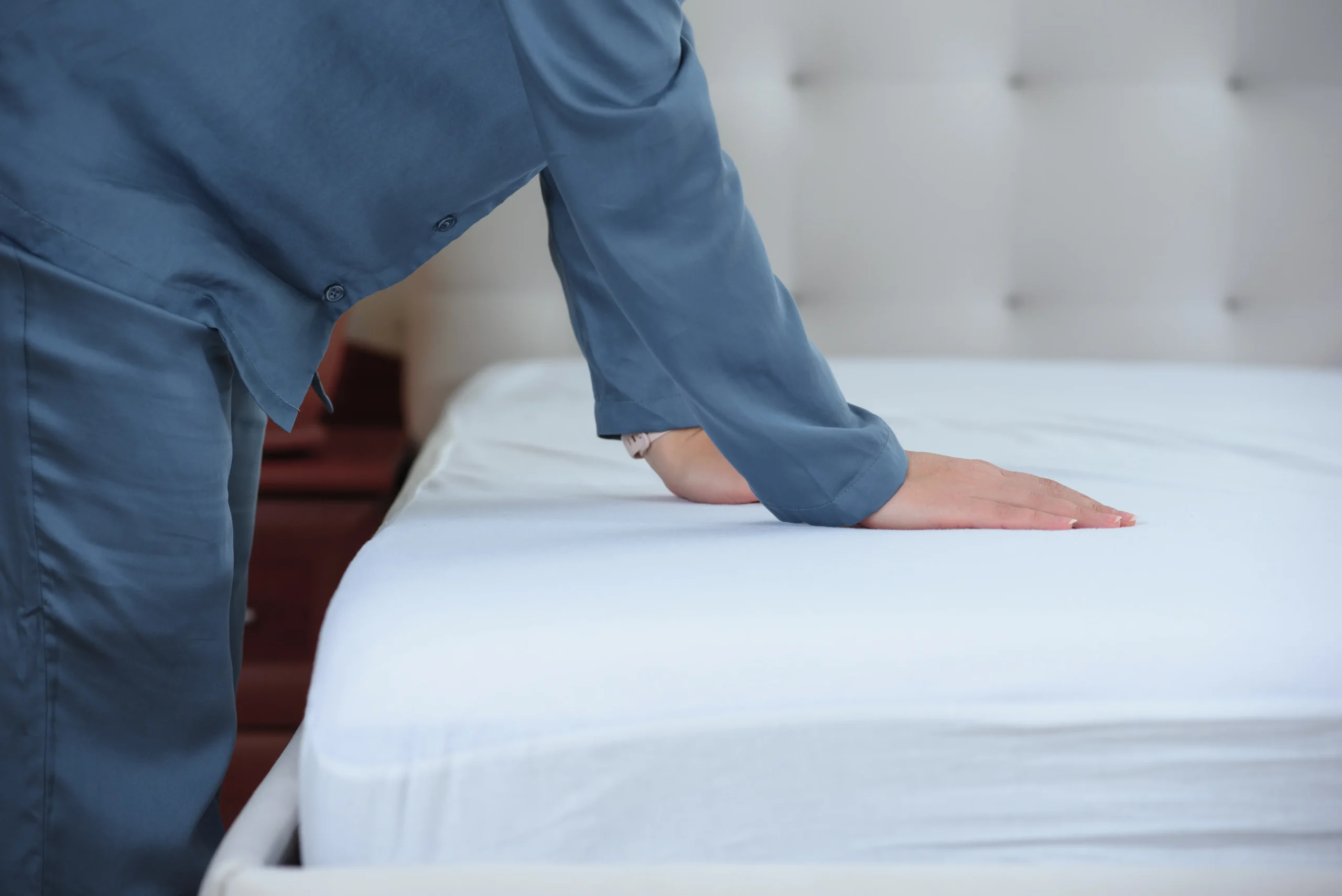 Personne testant la fermeté d'un matelas blanc en magasin pour soulager les douleurs de dos